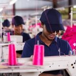 smiling african worker sewing in clothing factory